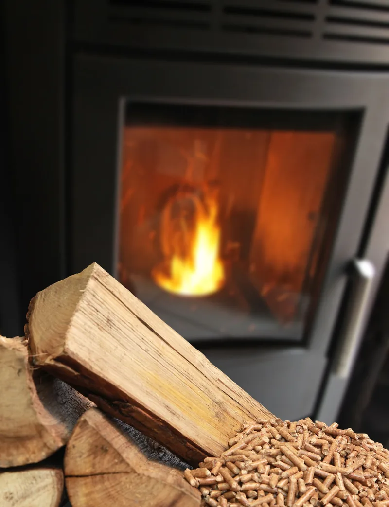 Poêle à bois en fonte noire, feu visible derrière la vitre.