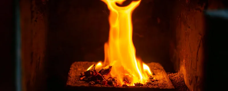 Des flammes brûlent dans une cheminée sombre.