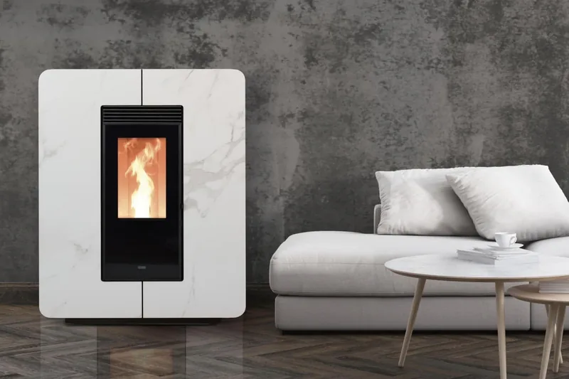 Un poêle à granulés noirs aux flammes vives est placé à côté d'un canapé bleu et d'une table d'appoint.